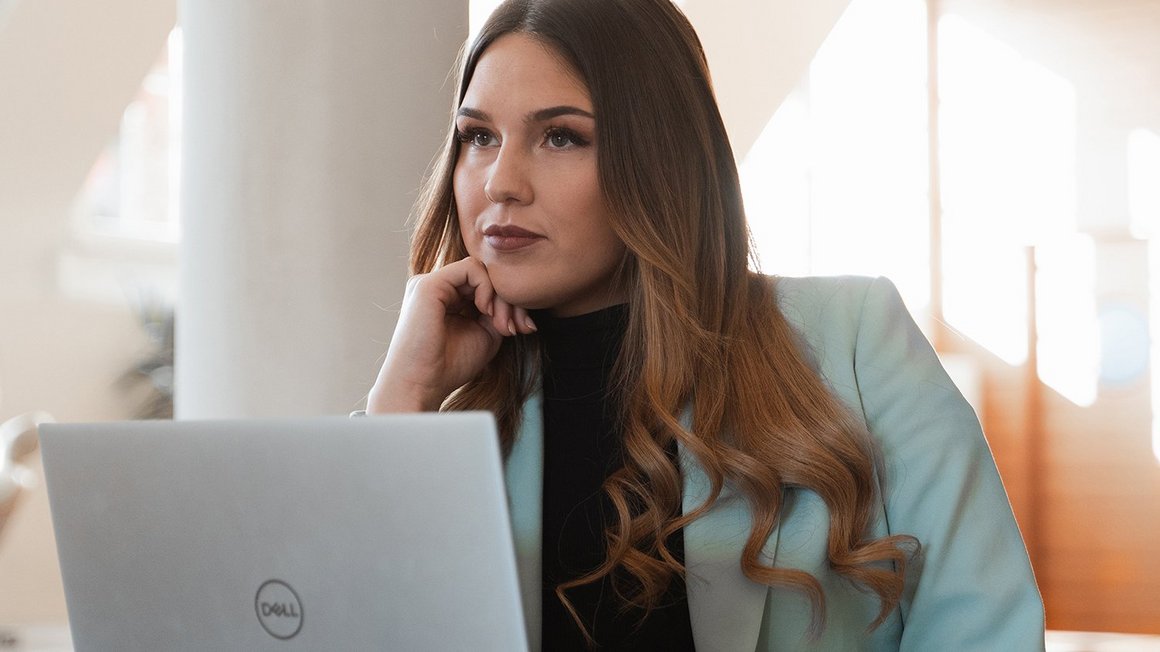 Woman sits at her laptop thinking