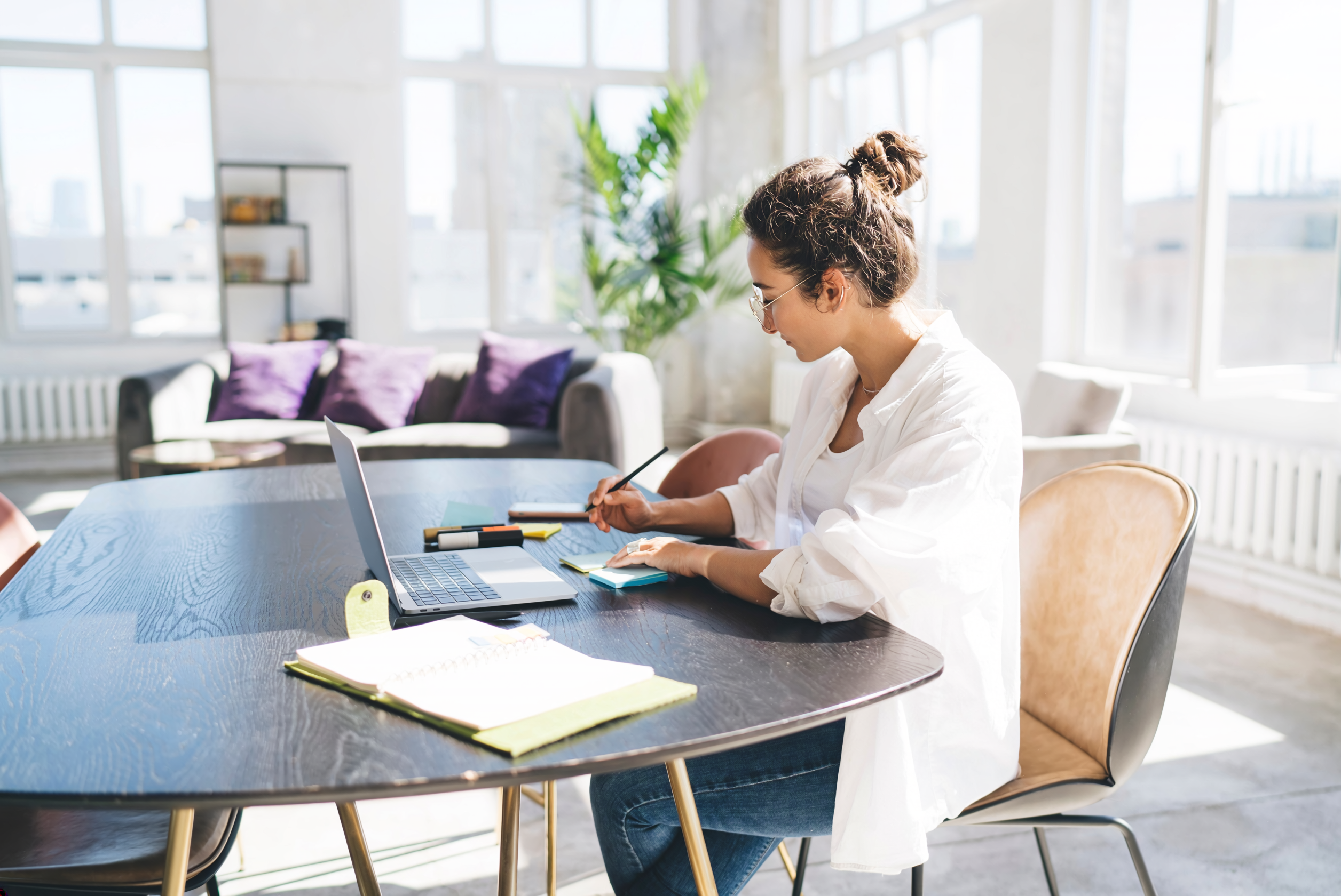 Eine Frau sitzt am Tisch, arbeitet und prüft ihren Fondssparplan