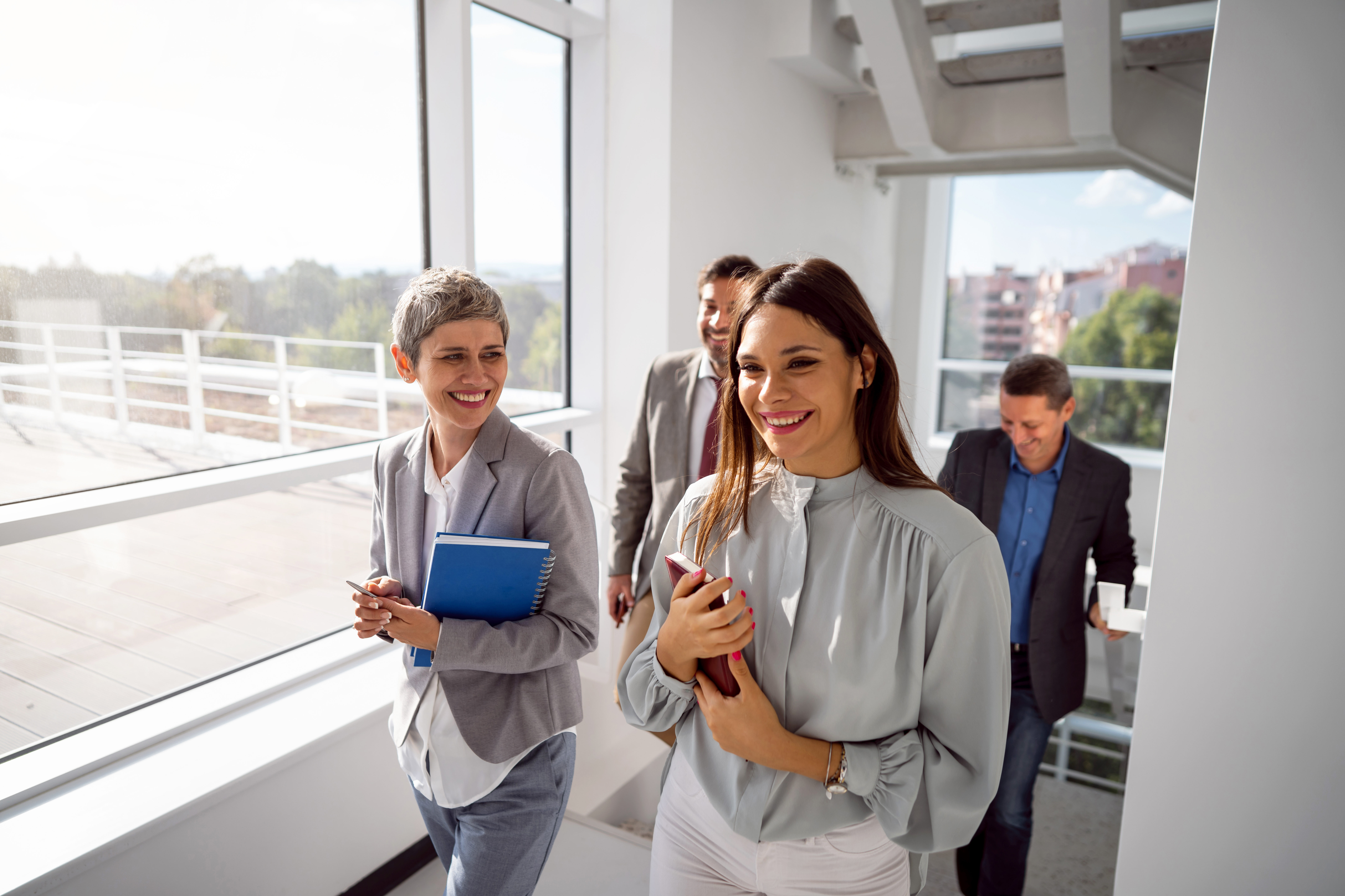 Photo of several cheerful people in business attire in a corridor