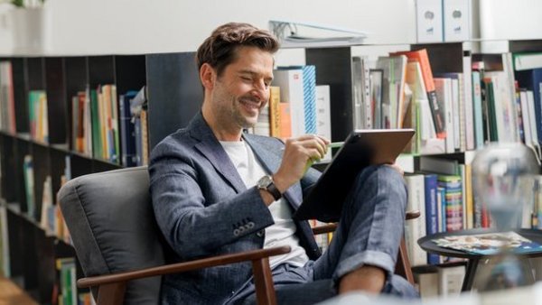 Man in a suit looks contentedly at a tablet – symbolises corporate responsibility and transparency guidelines.