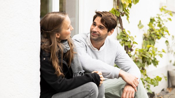 Junges Paar sitzt auf Stufen vor dem Haus