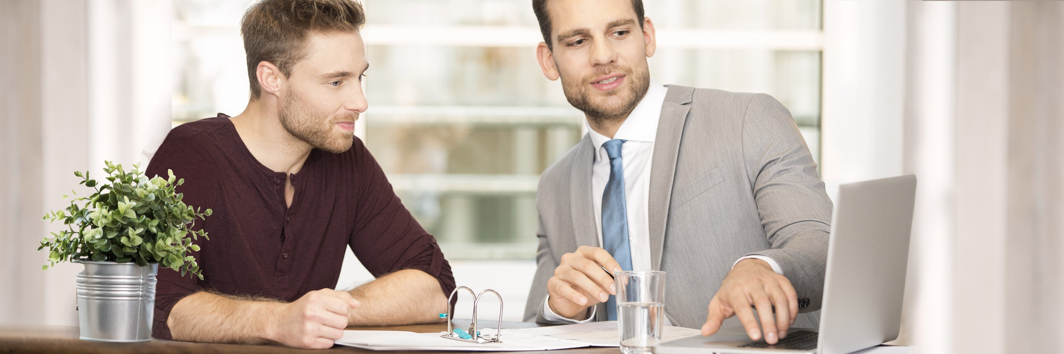 [Translate to english:] Finanzberater erklärt jungem Mann Altersvorsorge