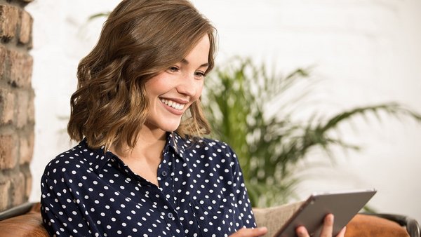 Young woman with tablet smiling with good money mindset