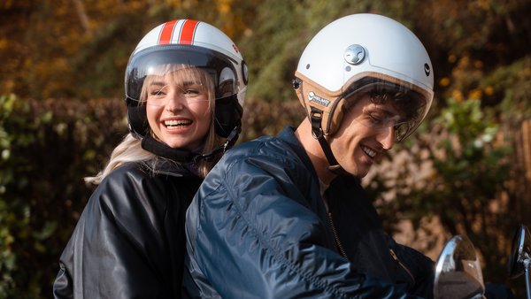 Young Couple is driving on a scooter.