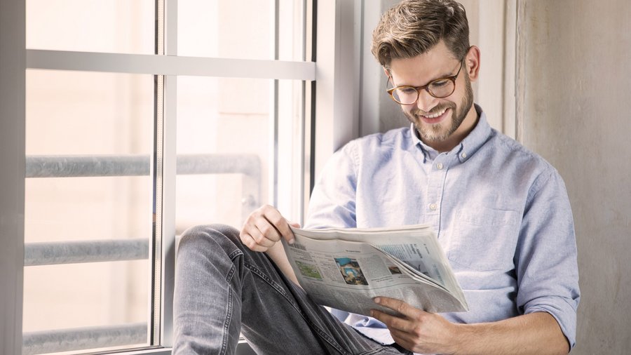 Foto deines Mannes der fröhlich eine Zeitung liest