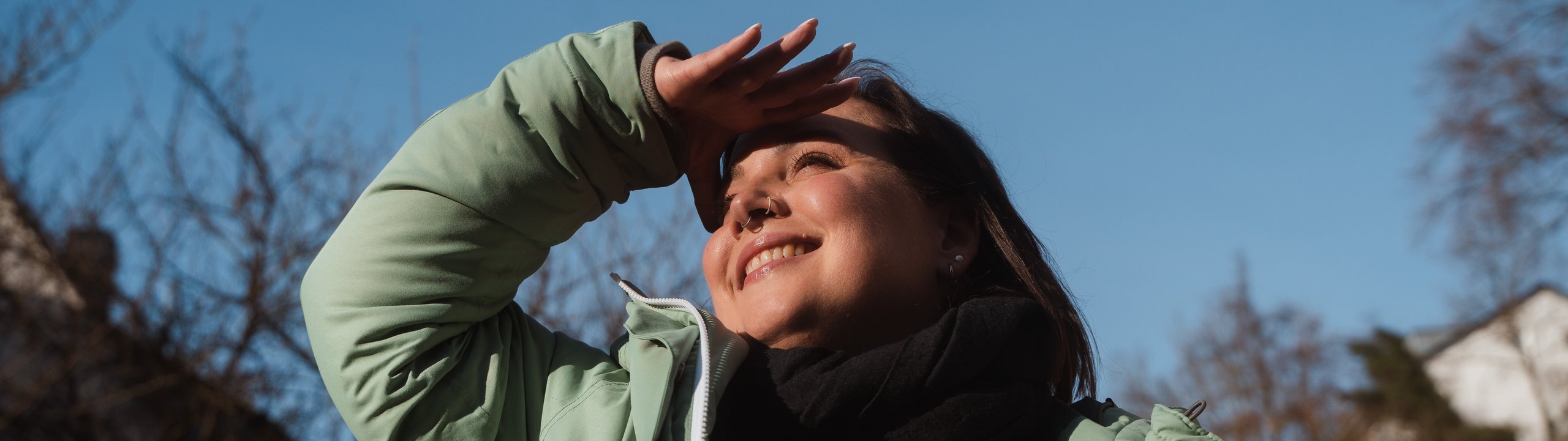 Young woman standing in nature, looking positively into the distance.