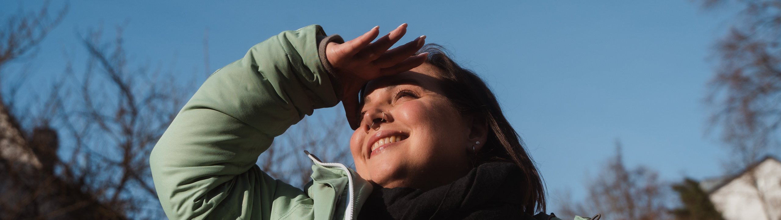 Junge Frau steht in der Natur und schaut positiv in die Ferne.
