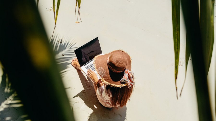 Woman working on the beach - remote work abroad