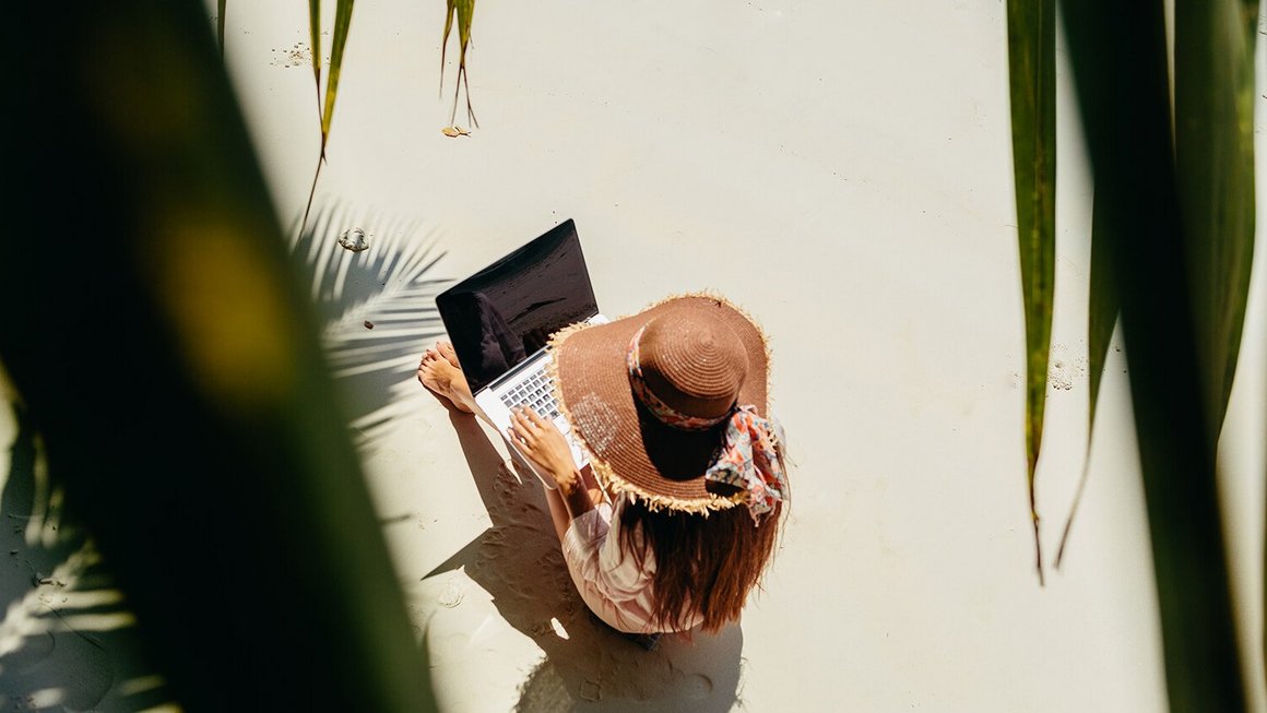 Frau arbeitet am Strand – Remote Work im Ausland