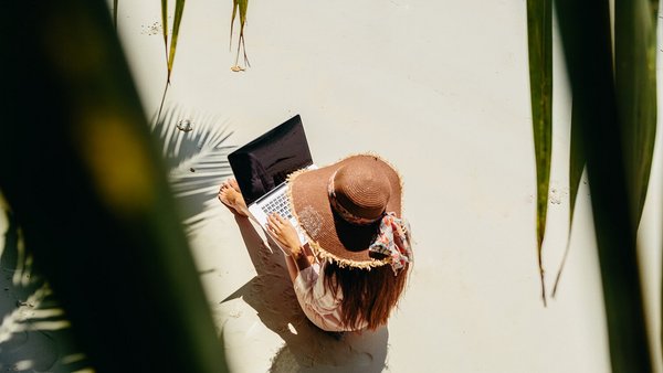 Woman working on the beach - remote work abroad