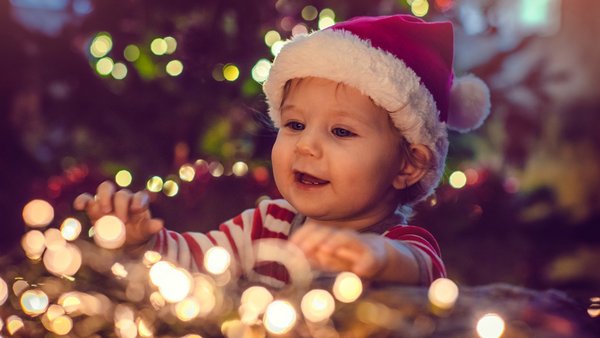 Kind mit Weihnachtslichtern und Weihnachtsmütze – Soziale Verantwortung und Charity