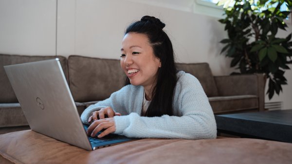 Woman smiles while reading on a tablet in a modern interior.