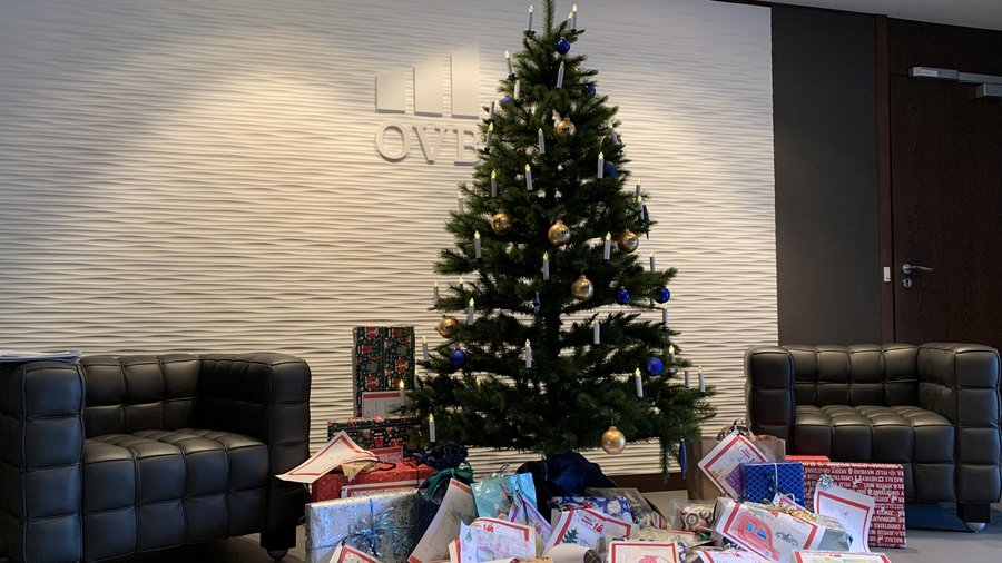 Geschmückter Weihnachtsbaum im Foyer der OVB Zentrale am Kölner Heumarkt. Vor dem Weihnachtsbaum liegen viele eingepackte Geschenke