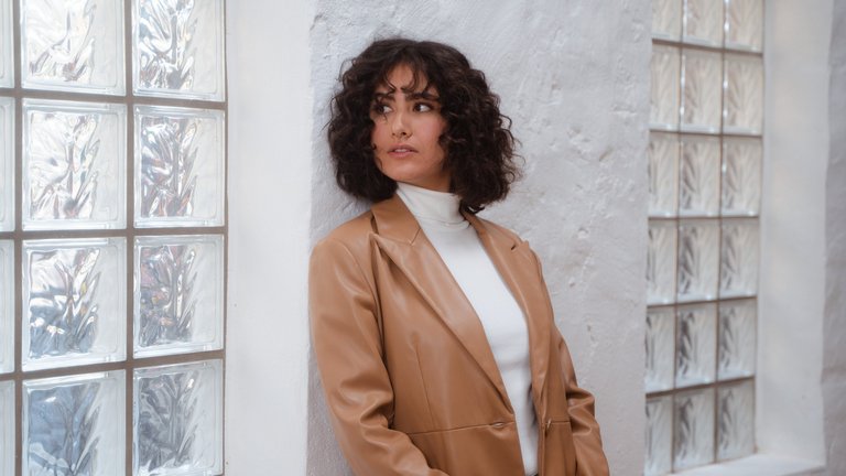 Young woman smiles and leans against a wall