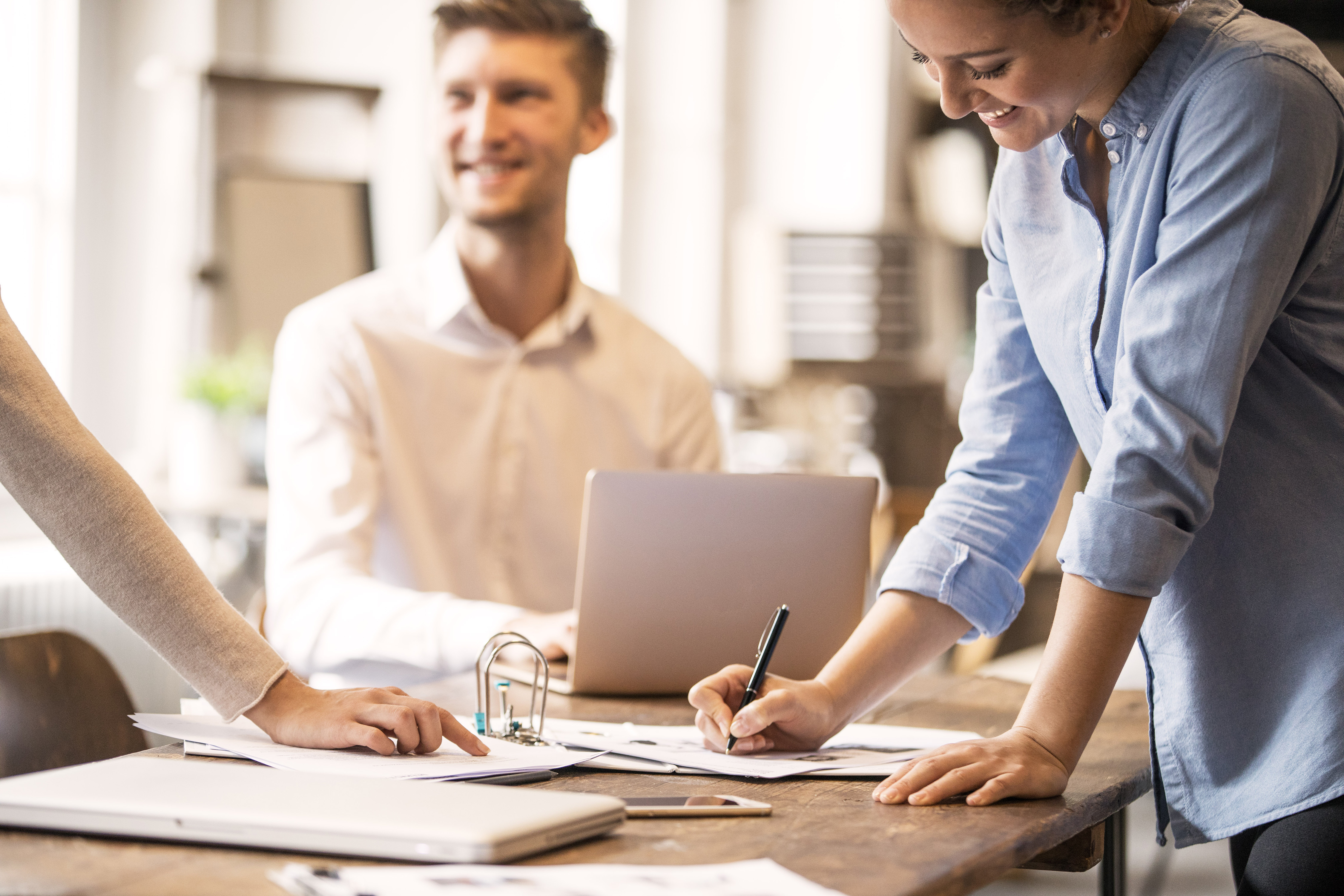 Drei Personen arbeiten gemeinsam an einem Tisch im Büro